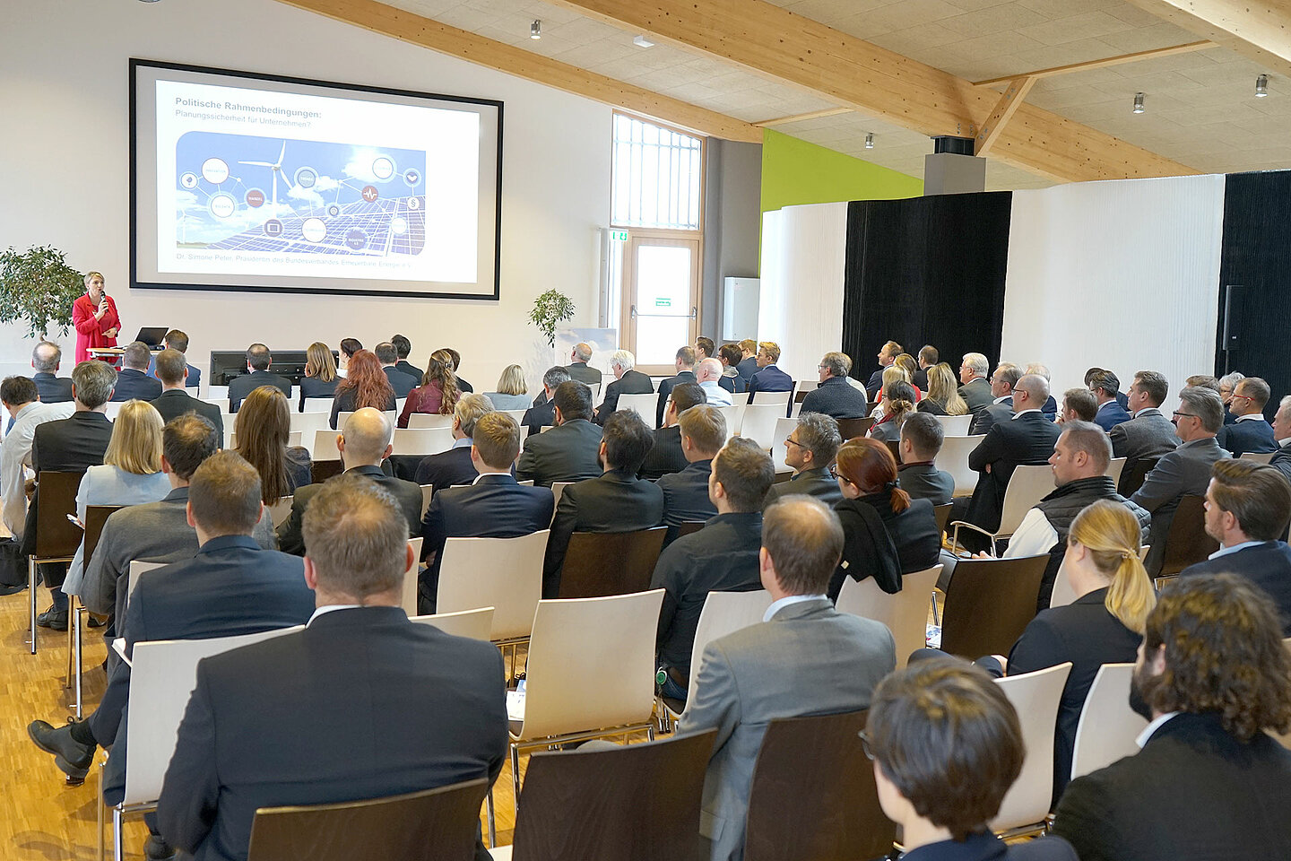 Eine große Leinwand zeigt eine Präsentation, die vor vielen Personen gezeigt wird