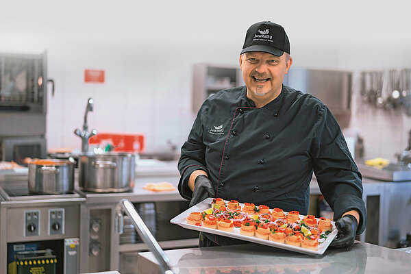 Küchenchef Jens präsentiert dekoriertes Fingerfood